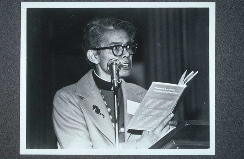 Pauli Murray standing in front of a microphone, reading from Dark Testament and Other Poems